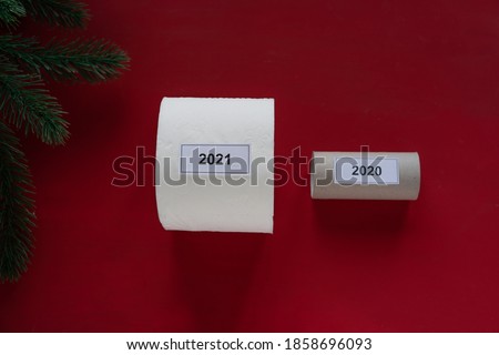 A fresh start for 2021. Two toilet paper rolls on a red background with a pine tree. New year celebration. 2020 vs. 2021