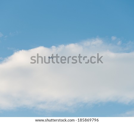 Airplane is flying in the sky among clouds.