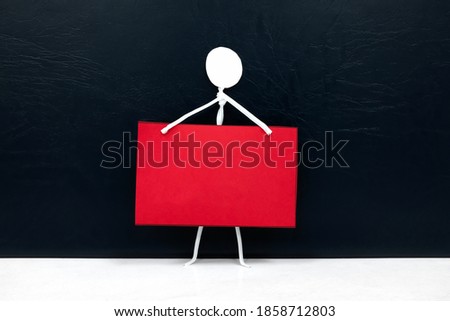 One stick man figure holding blank red placard or notice or announcement board in black background. Activism, protest, demonstration, social movement and freedom of expression template concept.