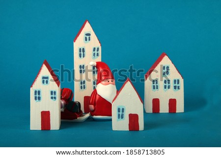 Santa Claus with sleigh of gifts walking among houses of toy city - new year concept. Image contains copy space