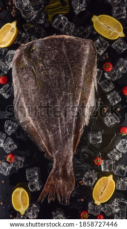 headless halibut with ice, lemon and tomatoes on black background
