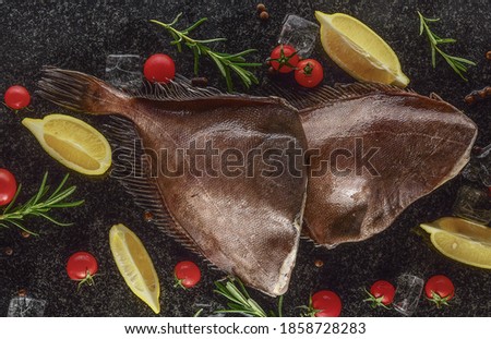 headless halibut with ice, lemon and tomatoes on black background