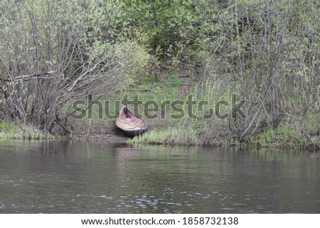The view of water of forest river  with old boat on its coast.