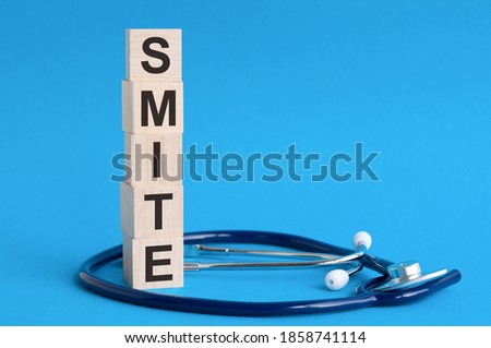 Smite word written on wooden blocks and stethoscope on light blue background, insurance and medical concept