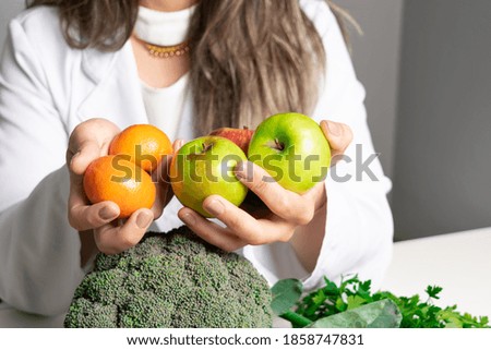 Female nutritionist in her office,  showing healthy vegetables and fruits. Healthcare and diet concept. Lifestyle.