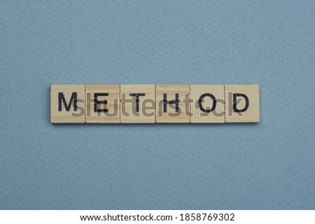 text the word method from brown wooden small letters with black font on an gray table