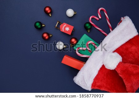 Santa hat with gifts on blue background . balls and candy cane