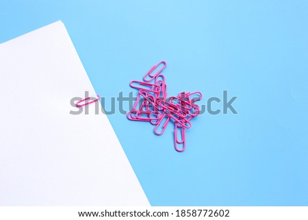 Pink paper clips on blue background.