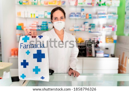 young pretty girl pharmacist with a bag whose word means "pharmacy" holding it up to deliver it Royalty-Free Stock Photo #1858796326