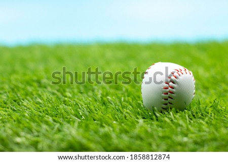 Baseball is on green grass with blue sky background