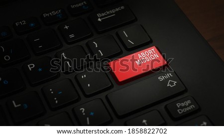 Close-up ABORT MISSION button with red color on a black laptop keyboard background. Conceptual photo to end or terminate something before completion on computer. IT protection on viruses.