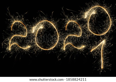 Happy New Year 2020 - 2021 light. Sparklers draw figures. Creative bengal lights and letter. Numbers written sparkling sparklers isolated on black background, space for text. Template for holiday card