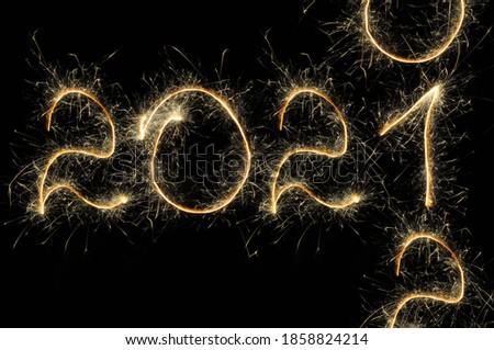 Happy New Year 2021 light. Sparklers draw figures. Creative bengal lights and letter. Number 2020 written sparkling sparklers between 2020 and 2022 isolated on black background, space for text.