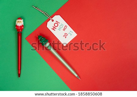 Merry Christmas and happy new year concept. pens with christmas symbols santa claus and christmas tree on a green and red background. Ho ho ho 2021