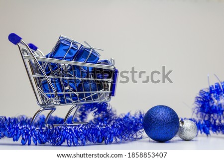Small shopping cart with blue gift and decoration on white backgorund. Merry christmas sale, copy space