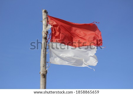 A Torn Indonesian Flag with a Blue Sky Background