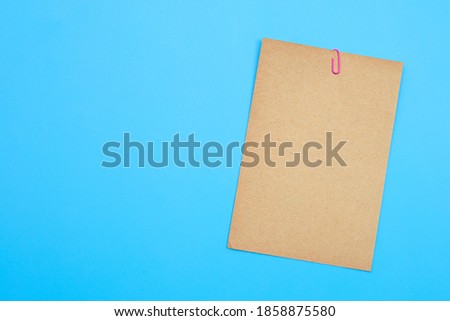 Brown paper with clip on blue background.
