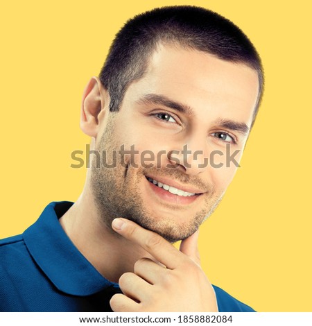 Portrait of happy smiling thoughtful young man, isolated over yellow color background. Male brunette model. Square composition studio image
