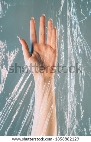 Plastic pollution. Save nature. Ecology problem. Waste reduction. Female hand floating underwater in clear creased polyethylene film isolated on blue background.