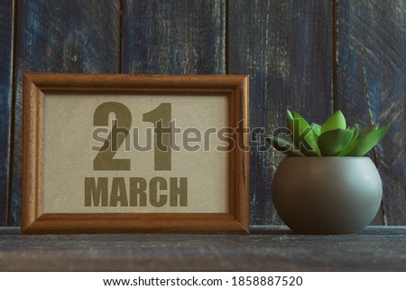 march 21st. Day 20 of month,  date in frame next to succulent on wooden background spring month, day of the year concept.