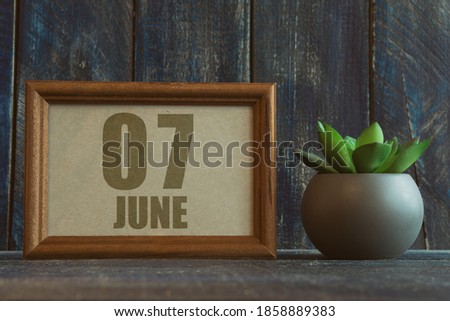 june 7th. Day 7 of month,  date in frame next to succulent on wooden background summer month, day of the year concept.