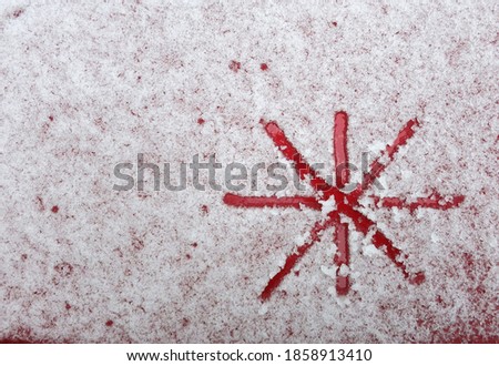 Painted snowflake in the snow on the red hood of the car      
