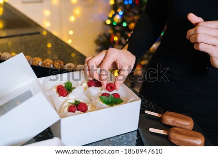 Chef hands is holding homemade christmas cupcakes with fruit. Happy New Year and Merry Christmas Background. Winter decorations over dark background with defocus xmas tree light. Selective Focus.