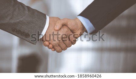 Business people in office suits standing and shaking hands, close-up. Business communication concept. Handshake and marketing