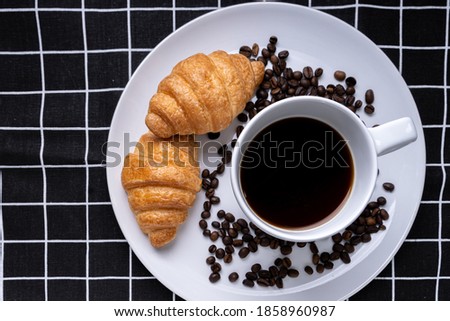 Delicious fresh croissants and coffee cup in plate on black Plaid pattern background. French breakfast. Tasty croissants with copy space