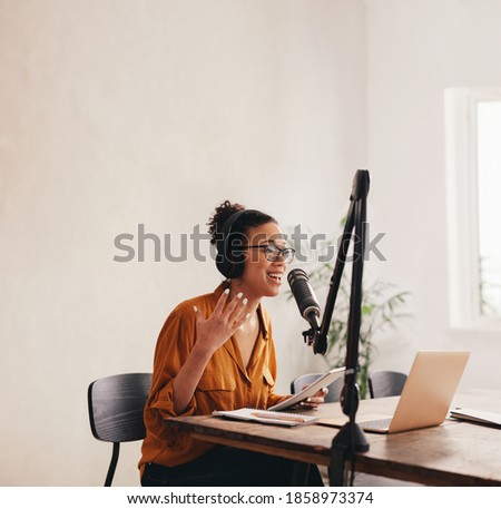 Professional female podcaster making a podcast from home studio. Woman working from home recording a podcast.