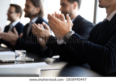 Crop close up of businessmen in formal suit sit ta desk in office applaud for presentation. Male employees businesspeople clap hands feel thankful for training. Appreciation, acknowledgment concept. Royalty-Free Stock Photo #1858990447