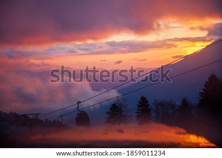 Krasnaya Polyana, Sochi, the mountains of the North Caucasus, snow-capped peaks against the background of autumn trees, red sunset over Krasnaya Polyana by cable car