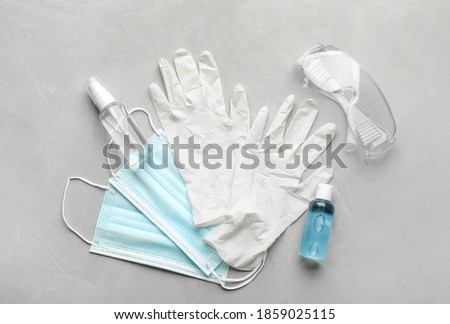 Flat lay composition with medical gloves, masks and hand sanitizers on grey background