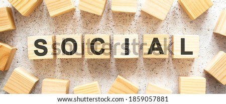 The word SOCIAL consists of wooden cubes with letters, top view on a light background.