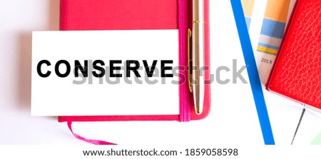 Text CONSERVE on white card lying on notepad on office desk. Financial concept.