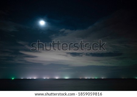 The moon and the stars at the sea with fishing boats