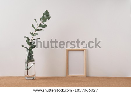 Frame and vase with eucalyptus on a white background. Mock up, copy space. Folk
