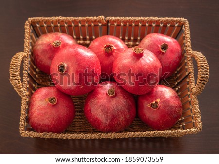 Fresh red Fruits Pomegranates in a basket. Wooden background.