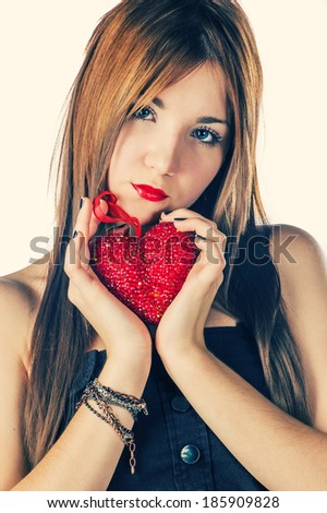 Cute girl holding decorative red heart in her hands