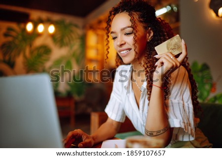 Young woman sitting at cafe making online shopping, using credit card and laptop. Online shopping, e-commerce, internet banking, spending money. Black Friday.