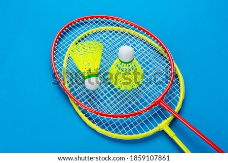 Two shuttlecock and badminton rackets on blue background. Active recreation and sports concept. Space for text. 