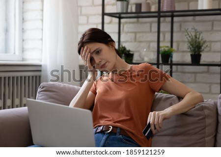 Unhappy young caucasian woman looking at computer screen, feeling stressed entering wrong payment information from credit card, having lack of money, financial problems or hacked bank account. Royalty-Free Stock Photo #1859121259