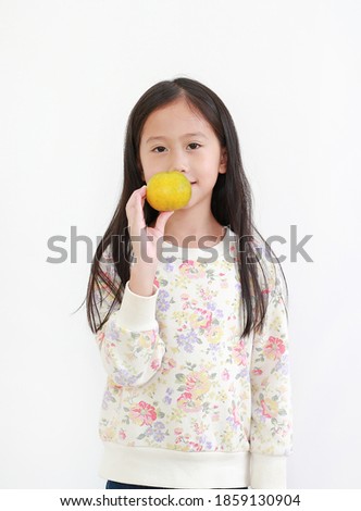 Portrait of little asian kid girl holding orange fruit on white background