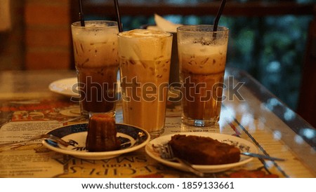 Ice coffee in a tall glass with cream poured over 