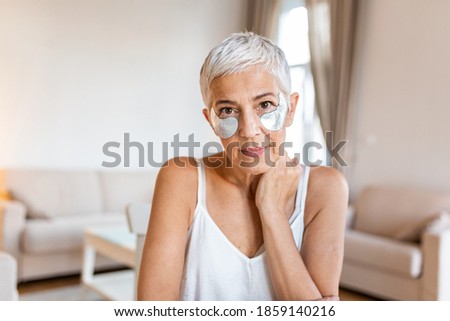 Beauty portrait of middle age woman with wrinkles and a silver patch under eyes. Collagen mask and spa concept. Copy space. Summer skin care