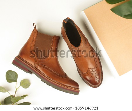 Women's brown shoes with perforations. Chelsea boots, magazine and leaves.