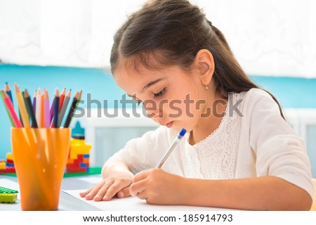 Cute little hispanic girl writing at school