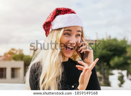 Stock photo of a beautiful blonde girl having a Christmas phone call while is laughing and having fun. Merry xmas, technology and communication concept