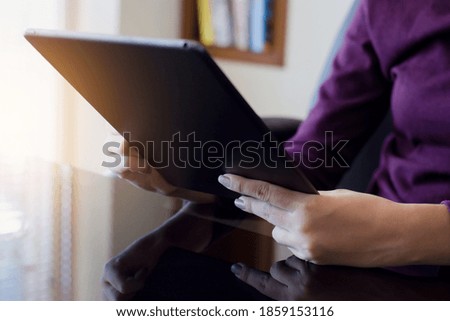 Casual woman hands holding and reading black digital tablet computer screen at workplace.