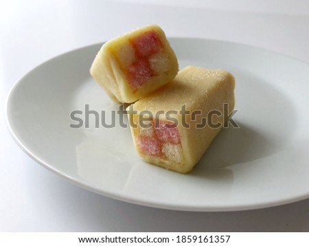 Closeup of Battenberg cake on white plate against a white background. Traditional colorful British cake wrapped in marzipan.